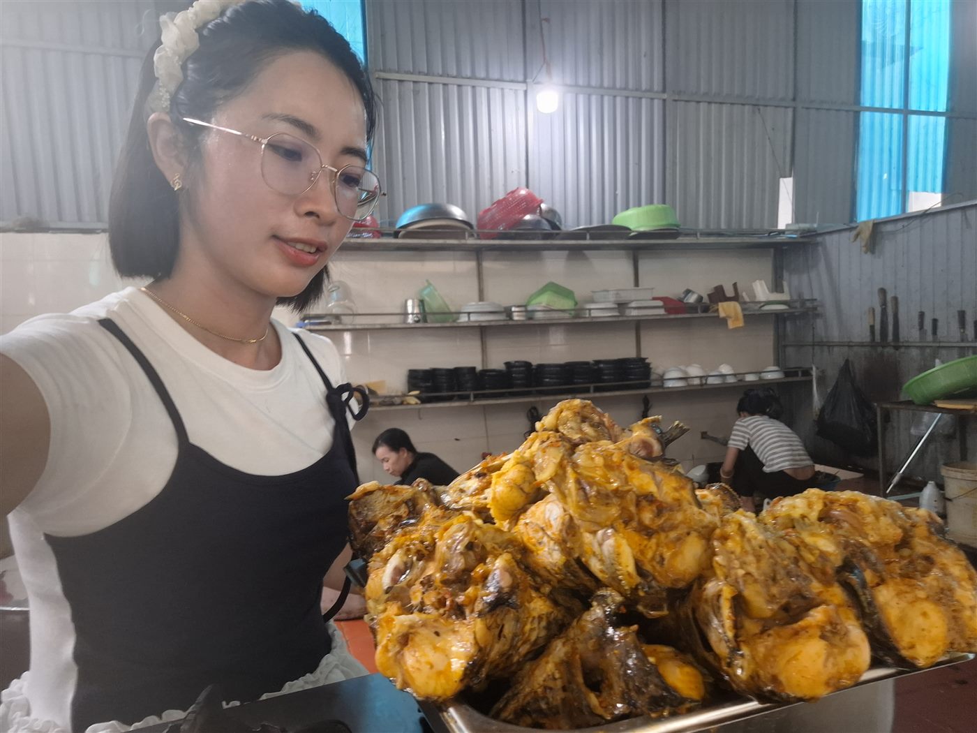 Đầu lòng cá lóc chiên vàng xếp đầy khay tại bếp Bánh Canh O Choa, chị Hồ Thị Oanh đứng bên cạnh
